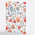 A notecard featuring a multicolored Nordic floral pattern with a mix of flowers and leaves in red, blue, orange, and grey tones on a white background, from The Uff Da Sisters.