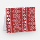 A red notecard with a traditional Nordic pattern consisting of white floral and geometric designs from The Uff Da Sisters.