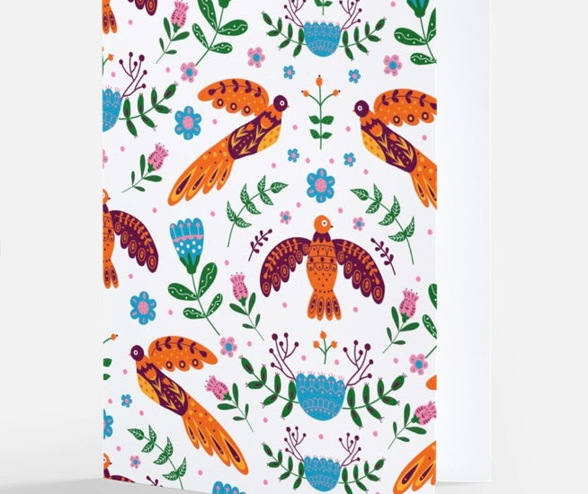  A white notecard adorned with a colorful Nordic-inspired pattern featuring stylized orange birds and a variety of floral elements, from The Uff Da Sisters.