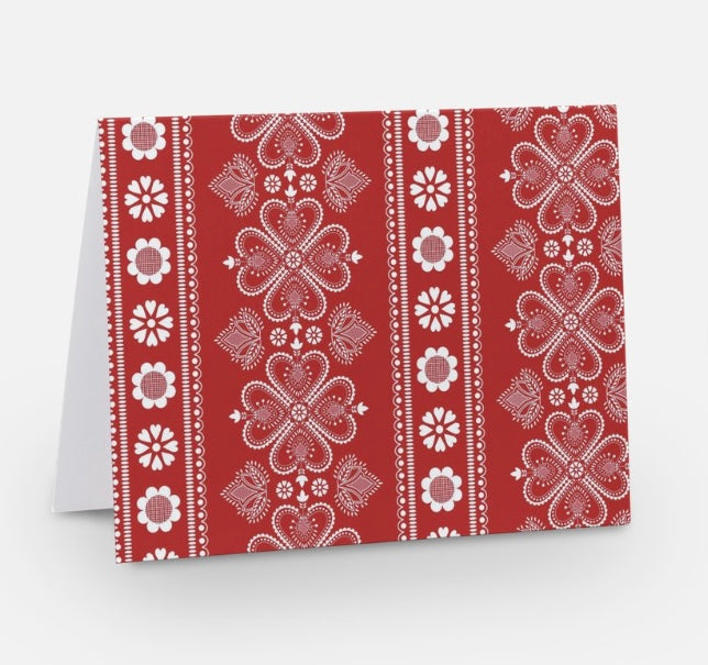  A red notecard with a traditional Nordic pattern consisting of white floral and geometric designs from The Uff Da Sisters.